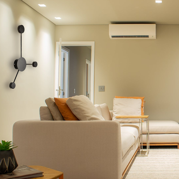 Une image d'un salon avec un canapé beige, une table basse, un tapis, une plante verte, un lampadaire noir et un climatiseur. MI-5571176954,MI-7812852164,MI-8767661955,MI-9890974096,