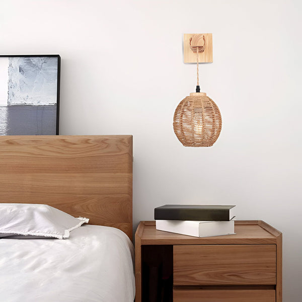 Une applique murale en rotin avec une ampoule à filament. L'applique est fixée à un mur blanc au-dessus d'une table de chevet en bois. Sur la table de chevet, il y a deux livres et une lampe. ER-557575426X,