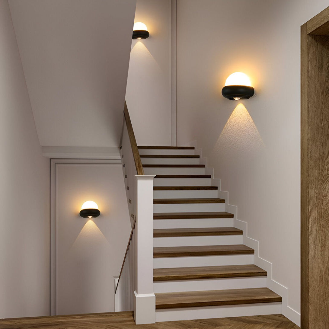 Une image d'un escalier en bois avec des murs blancs et des appliques murales noires. EX-8638596960,EX-4113421196,EX-0309017424,