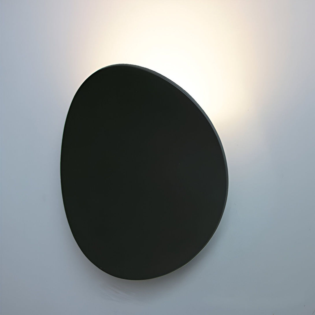 Une applique murale noire en forme de galet. DE-8054556632,DE-0853481989,DE-2502387817,DE-7283470557,DE-6011146961,DE-3639032594,DE-4151317678,DE-0168772612,DE-6626641387,DE-2260219322,DE-6307227001,DE-3738266372,DE-8511010173,DE-7036764996,DE-4587051241,DE-9018460893,DE-0632344601,DE-4256653104,DE-5000257235,DE-4700066563,DE-3834710490,
