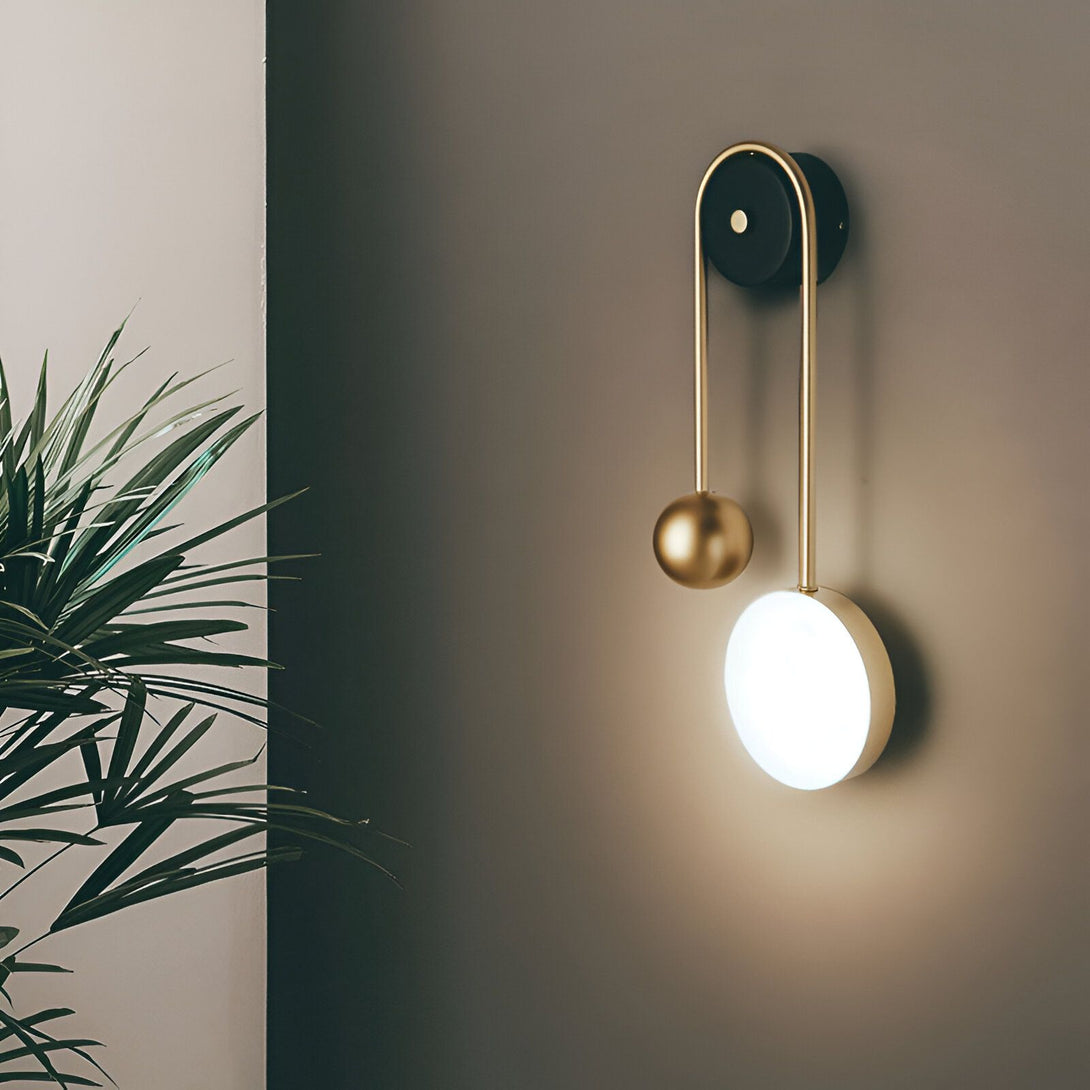Une applique murale noire avec une sphère en métal doré et un abat-jour rond en verre blanc. MI-5508556966,