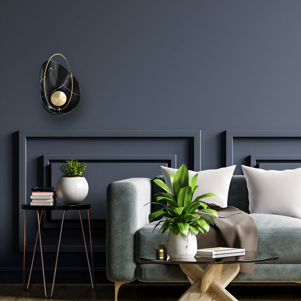 Une image d'un salon avec un canapé vert, une table basse, une plante verte, des livres et une applique murale noire et or. KA-5792512744,KA-0929180569,