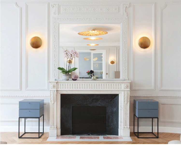 Une image d'une cheminée avec un miroir au-dessus. Il y a deux appliques murales de chaque côté de la cheminée. Il y a une orchidée sur le manteau de la cheminée. Il y a deux tables avec des tiroirs de chaque côté de la cheminée. EC-2203444304,EC-1181518121,EC-1128189976,EC-4141118907,