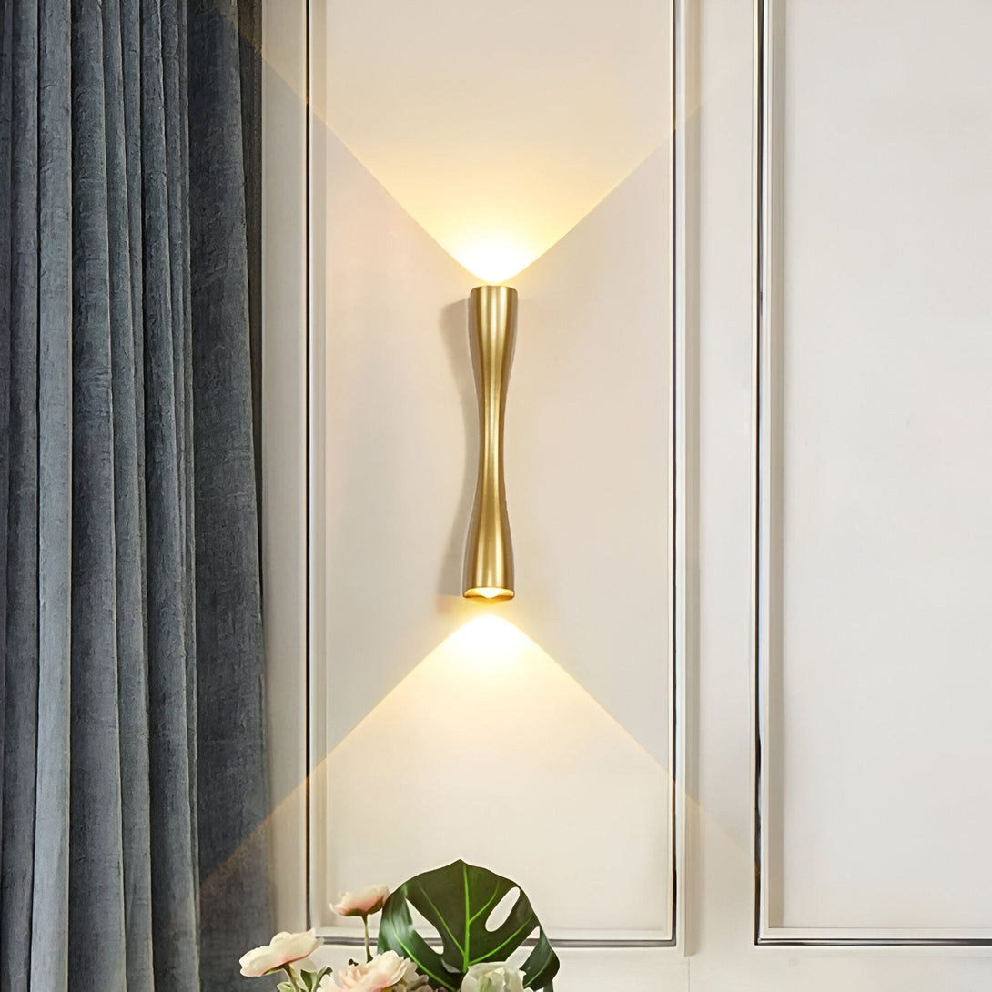 Une applique murale en laiton avec deux sources de lumière orientées vers le haut et le bas. L'applique est montée sur un mur blanc à côté d'un rideau gris. AT-4528101939,AT-0417275307,