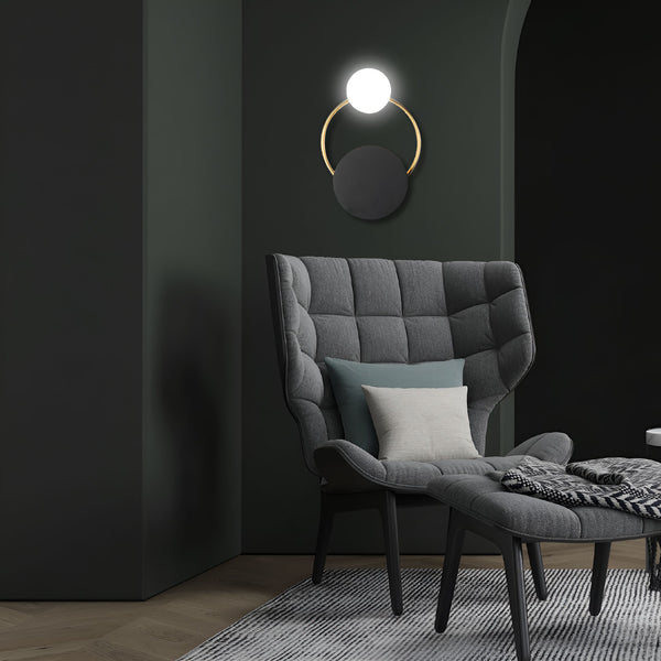 Une image d'un fauteuil gris avec un lampadaire noir et doré accroché au mur vert foncé. Il y a un tapis noir et blanc sur le sol. AL-0113600720,