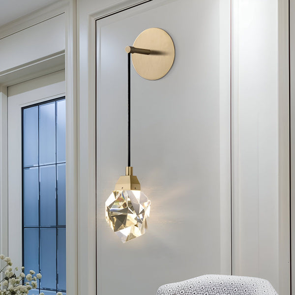 Une applique murale en cristal avec une finition en laiton. L'applique est de forme géométrique et est suspendue à un cordon noir. OP-5554030025,OP-6981510057,