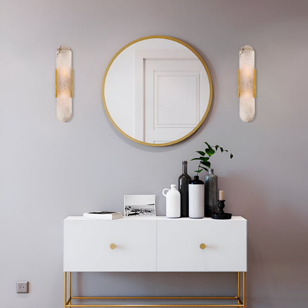 Une image d'une console blanche avec des poignées dorées, un miroir rond doré, et deux appliques murales dorées. Sur la console, il y a une plante verte, une bougie, et trois bouteilles en verre. FU-8330655202,FU-7846624369,FU-6574596262,FU-5000429826,