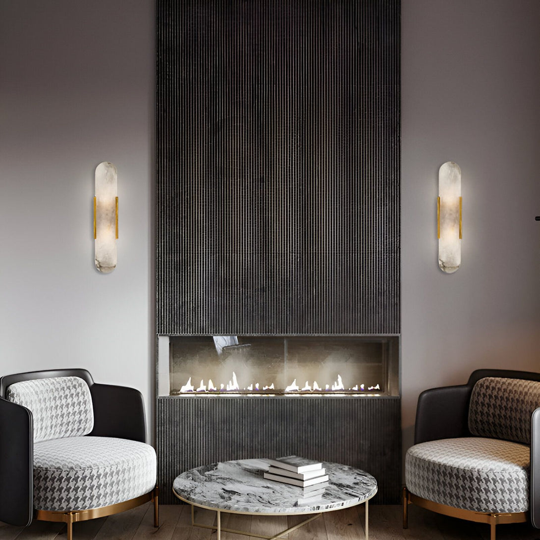 Deux appliques murales en marbre blanc et laiton sont disposées de chaque côté d'une cheminée. Au-dessus de la cheminée, un mur en pierre noire texturée. Devant la cheminée, deux fauteuils à motifs noir et blanc et une table basse en marbre blanc. FU-8330655202,FU-7846624369,FU-6574596262,FU-5000429826,