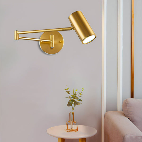 Une image d'une applique murale en métal doré avec un abat-jour cylindrique. L'applique est fixée au mur et diffuse une lumière blanche chaude. À côté, sur une table, se trouve un vase en verre transparent contenant des fleurs séchées. DE-9128165098,DE-7370131335,