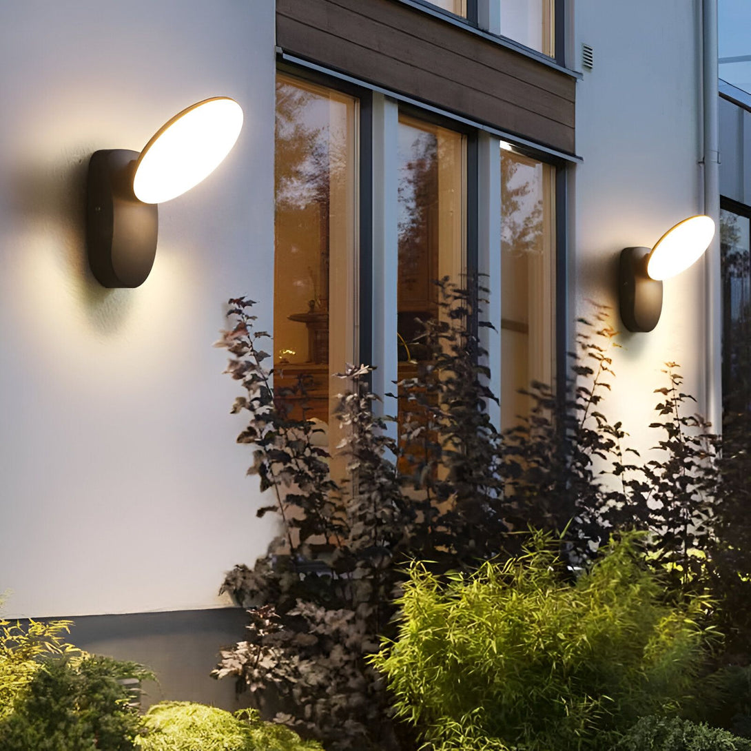 Une image d'une maison avec deux appliques murales extérieures noires. Les appliques sont en forme d'un demi-cercle et émettent une lumière blanche chaude. LI-7997035176,LI-6815012948,