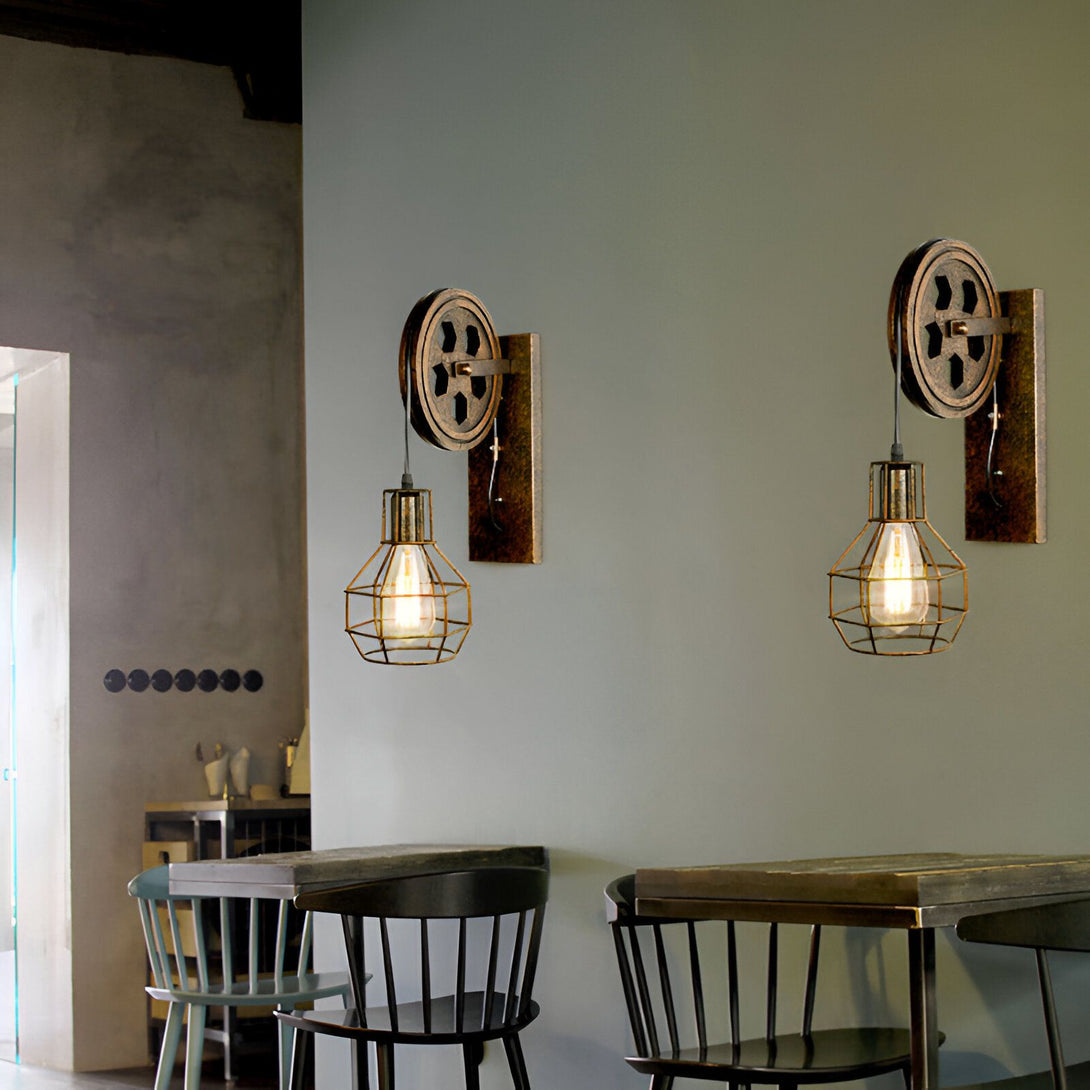 Une paire d'appliques murales industrielles avec des cages en métal et des poulies. JO-990895248X,JO-0941741435,JO-6688062364,JO-716467275X,