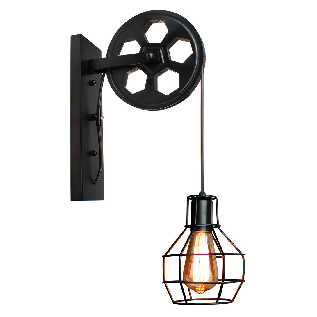 Une applique murale industrielle avec une poulie en métal noir et une cage en métal grillagé. L'ampoule est de couleur ambre. JO-990895248X,JO-0941741435,JO-6688062364,JO-716467275X,