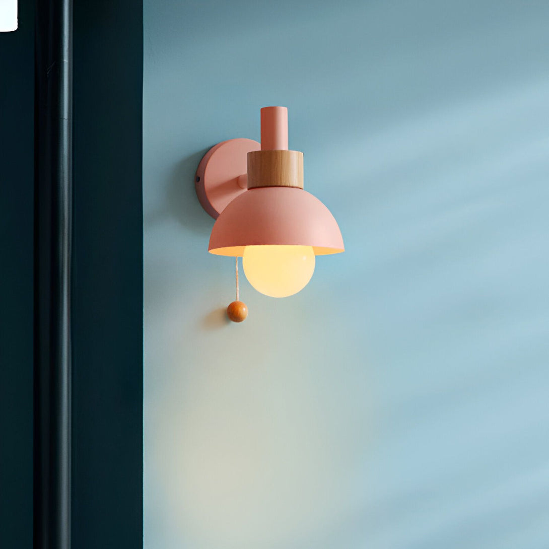 Une applique murale rose avec un abat-jour en métal et un interrupteur en bois. Le mur est bleu. CU-0994507933,CU-6034342961,CU-307088881X,CU-4880091847,CU-0283329386,CU-3398585787,CU-2087585903,CU-7230351375,