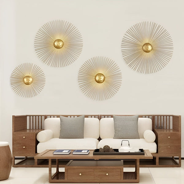 Quatre sculptures murales en métal doré en forme de soleil sont disposées sur un mur blanc. Un canapé blanc se trouve en dessous. Il y a une table basse en bois avec des livres dessus. HE-8816391111,HE-2490606875,HE-9117310997,HE-1528780337,