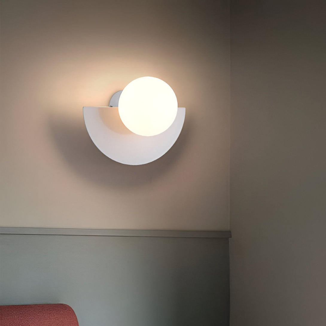 Une applique murale blanche en forme de demi-lune avec une boule en verre opalin. GU-5717952775,GU-9785984192,GU-5756525742,GU-2770483412,GU-259462313X,GU-7909977727,GU-9845973795,GU-8738437147,GU-6622229414,GU-8570558481,GU-3445094918,GU-3069247571,GU-5711512889,GU-8453761582,GU-7173945844,