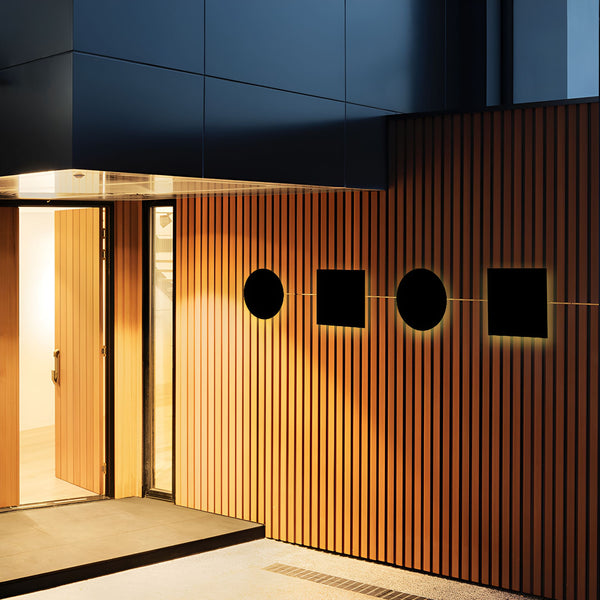 Une image d'une porte d'entrée en bois avec un mur en bois à côté. Il y a quatre appliques murales noires sur le mur en bois. LU-0937357146,LU-3212409584,LU-4507839009,LU-6078572369,