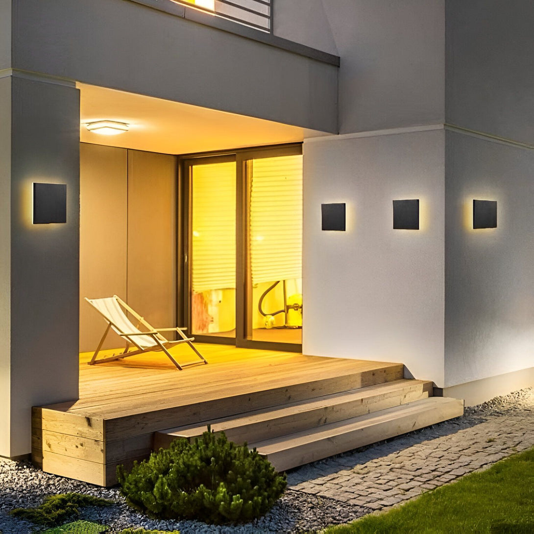 Une image d'une maison avec des lumières LED carrées noires modernes sur le mur extérieur. Les lumières sont allumées et projettent une lumière chaude sur le mur. LU-0937357146,LU-3212409584,LU-4507839009,LU-6078572369,