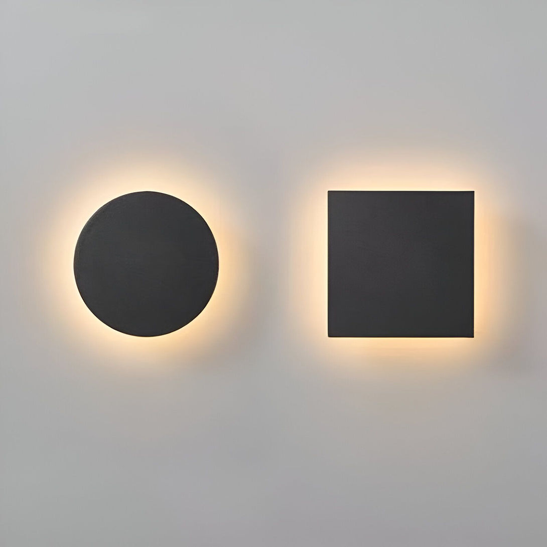 Deux appliques murales noires, l'une ronde et l'autre carrée, émettent une lumière chaude et diffuse. LU-0937357146,LU-3212409584,LU-4507839009,LU-6078572369,