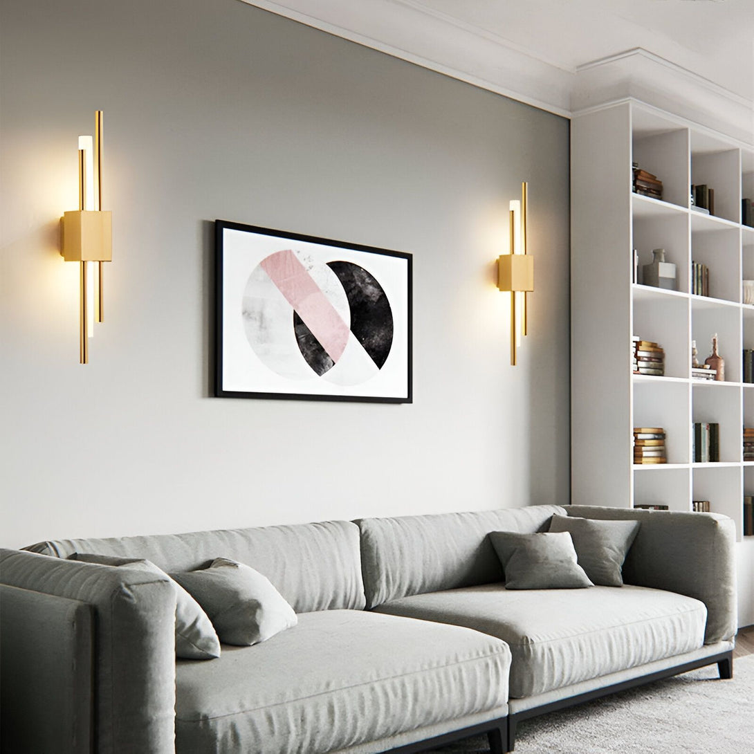 Une image d'un salon avec un canapé gris, une table basse et une bibliothèque. Il y a deux appliques murales dorées de chaque côté du canapé. IS-4341432532,IS-4576368761,