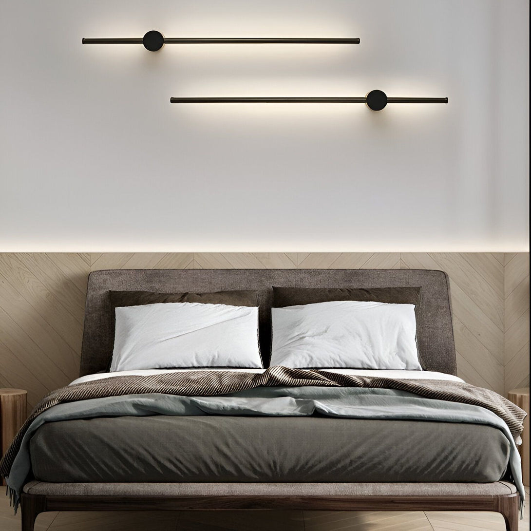 Deux appliques murales noires sont fixées au mur au-dessus d'un lit. Les appliques sont de forme cylindrique et émettent une lumière blanche. Le lit est recouvert d'une couette et de deux oreillers blancs. EM-4460156156,EM-9491391119,EM-7091335104,EM-2714779395,EM-6441388103,EM-2437079734,EM-5590103177,EM-2150536102,EM-957599227X,EM-8860104084,EM-8098031608,EM-5940573193,