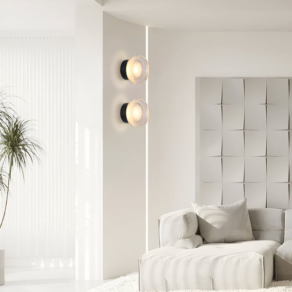 Deux appliques murales rondes en verre dépoli avec un fond doré. Les appliques sont fixées sur un mur blanc à côté d'un canapé blanc. LU-0727730975,LU-5113261599,