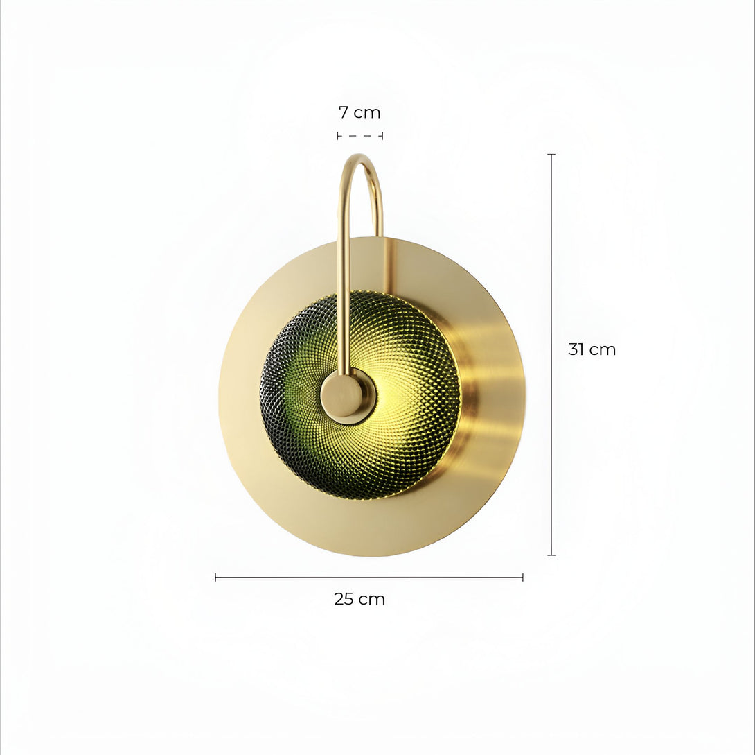 Une applique murale en laiton avec un diffuseur en verre vert. L'applique a une forme ronde et mesure 25 cm de diamètre. Le diffuseur en verre est de couleur vert foncé et a une texture striée. L'applique est fixée au mur par une plaque ronde en laiton. LE-4316598880,LE-6897461202,