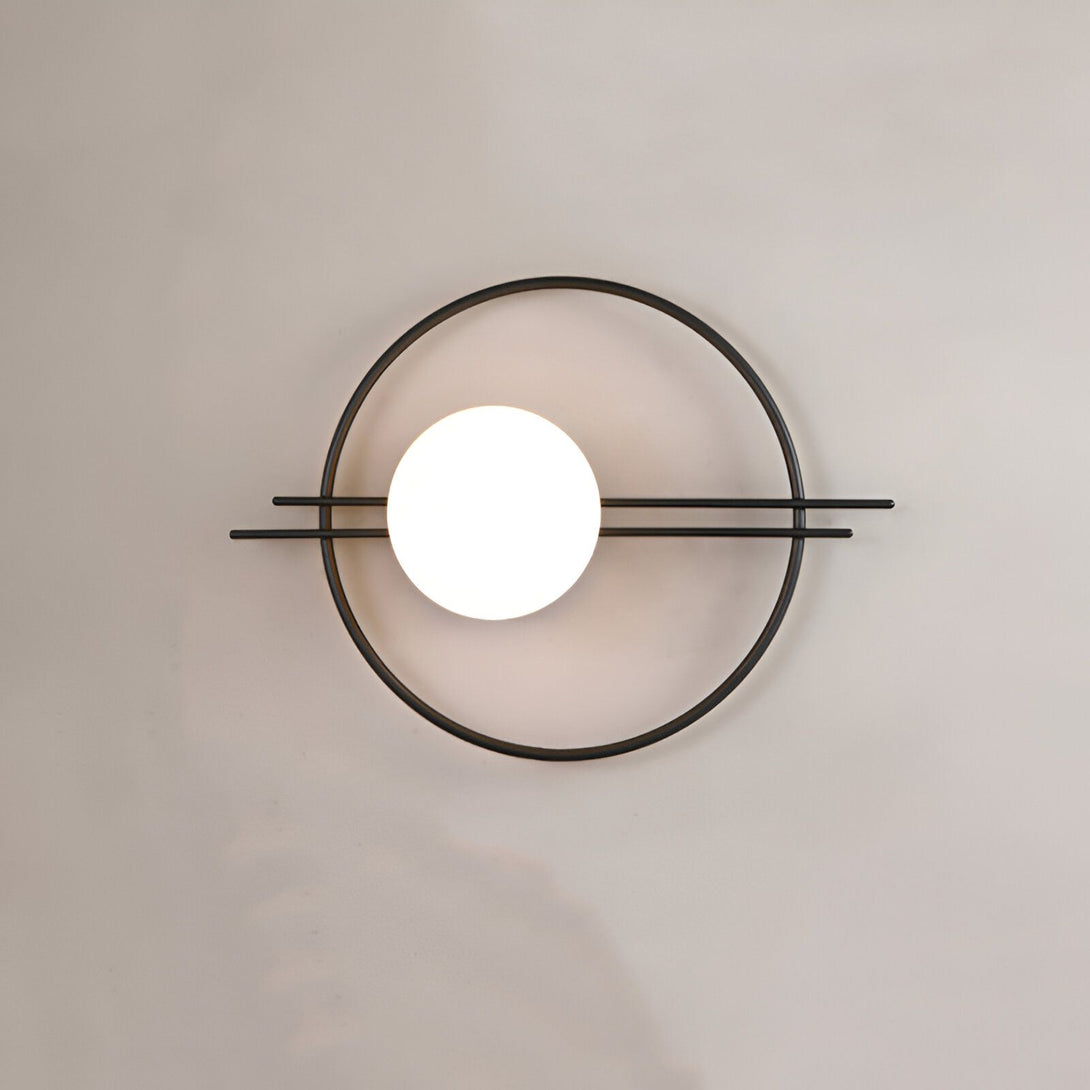 Une applique murale avec une forme géométrique. L'applique est de couleur noire et blanche. Elle est composée d'un cercle en métal noir et d'une sphère en verre blanc. La sphère est située au centre du cercle. L'applique est fixée au mur par deux tiges en métal noir. HE-738953074X,HE-993358930X,HE-6888843173,HE-0002139596,HE-7137387454,HE-7408799672,