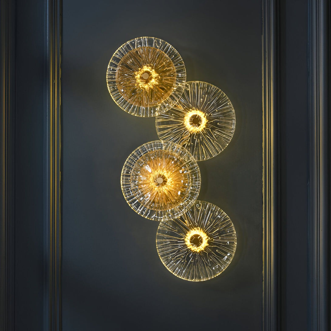 Quatre appliques murales rondes en verre transparent avec une lumière dorée à l'intérieur. Les appliques sont disposées verticalement sur un mur gris foncé. AZ-1516305086,AZ-9770102490,