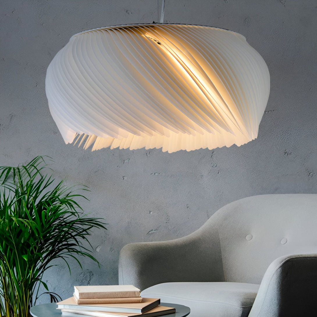 Une lampe en papier blanc est suspendue au plafond. La lampe est en forme de spirale et diffuse une lumière douce. Il y a un fauteuil gris et une plante verte à côté. LI-2975946449,LI-0269909052,LI-3785723539,LI-9818085345,