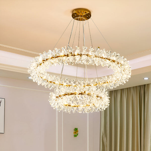 Une vue magnifique d'un lustre en cristal doré à deux niveaux. Le lustre est composé de plusieurs anneaux de cristaux transparents et de pampilles en cristal. Il est suspendu au plafond par un fil doré. EK-1487295170,EK-2785100514,EK-4427580491,EK-6790730826,