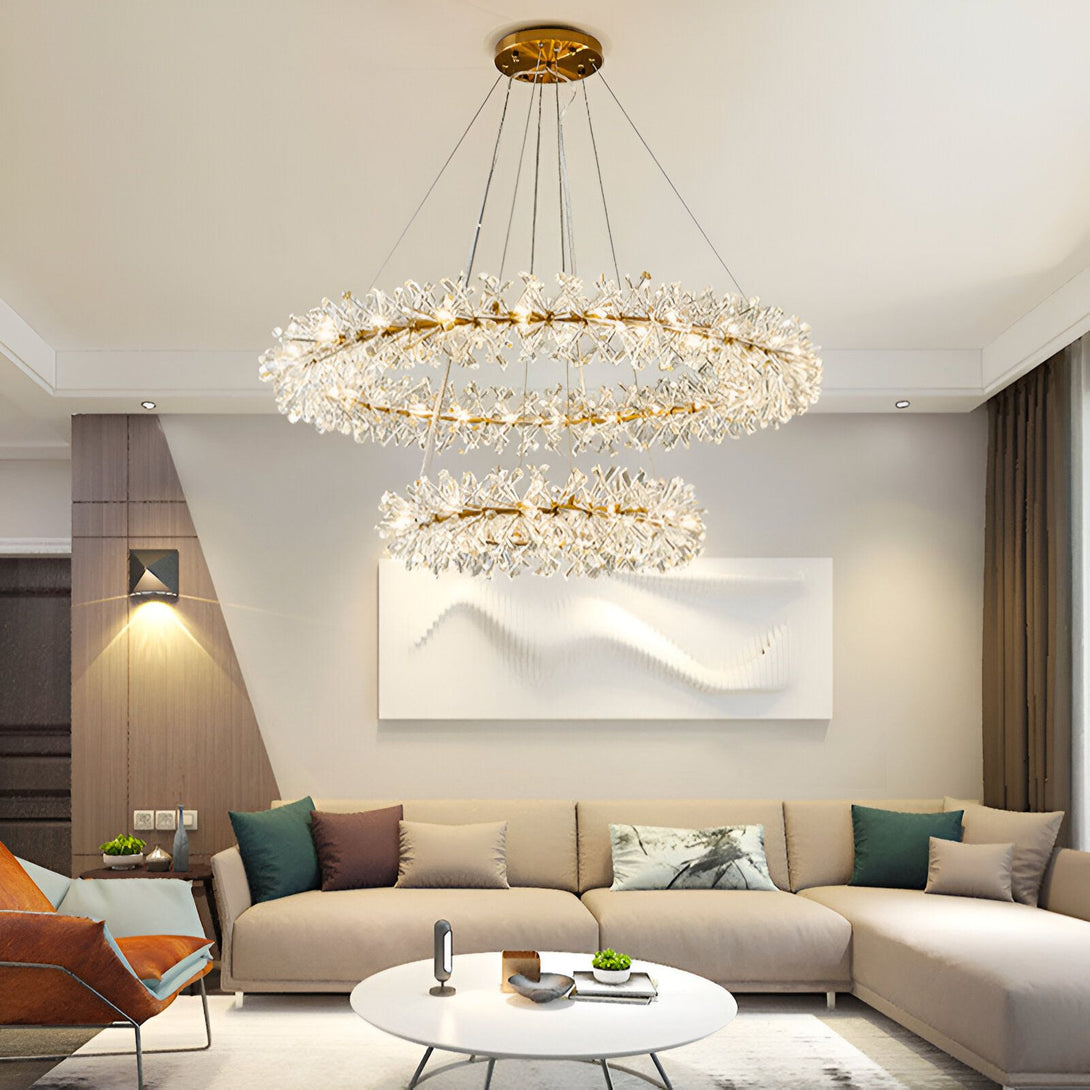 Une image d'un salon avec un lustre en cristal doré à deux anneaux. Le lustre est suspendu au plafond et est composé de nombreuses branches de cristal qui s'étendent vers l'extérieur. Il y a un canapé beige et une table basse dans le salon. EK-1487295170,EK-2785100514,EK-4427580491,EK-6790730826,