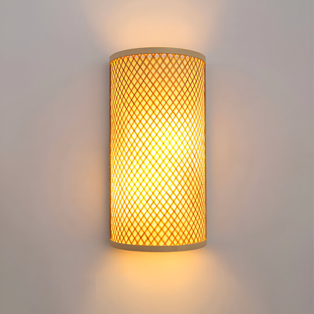 Une applique murale en bambou ajouré de forme cylindrique émettant une lumière tamisée. DE-7247857110,