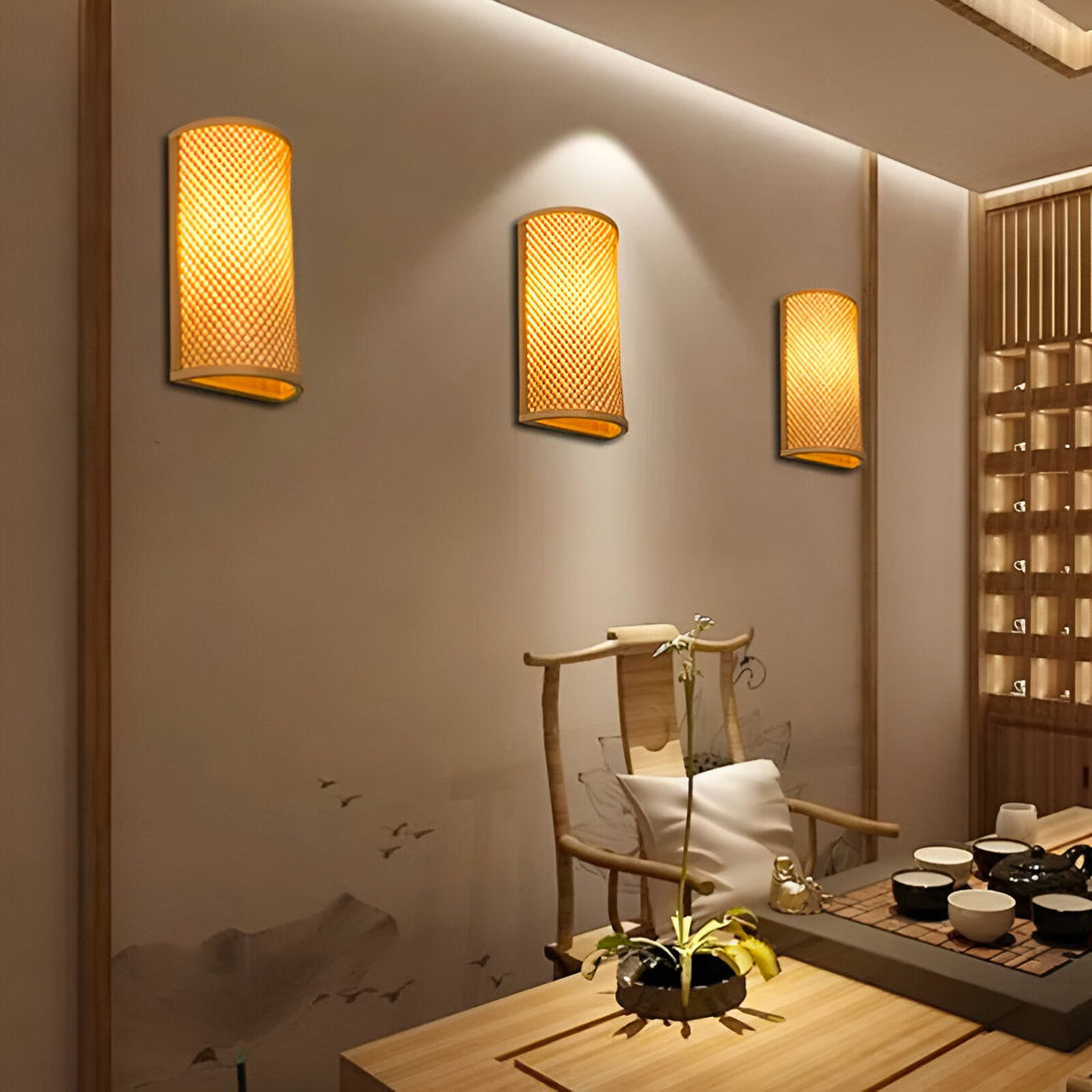 Une image de trois appliques murales en bambou. Les appliques sont de forme rectangulaire et sont faites de lattes de bambou tressées. Elles sont fixées au mur par une plaque en métal. La lumière est diffusée à travers les lattes de bambou, ce qui crée un effet tamisé et chaleureux. DE-7247857110,