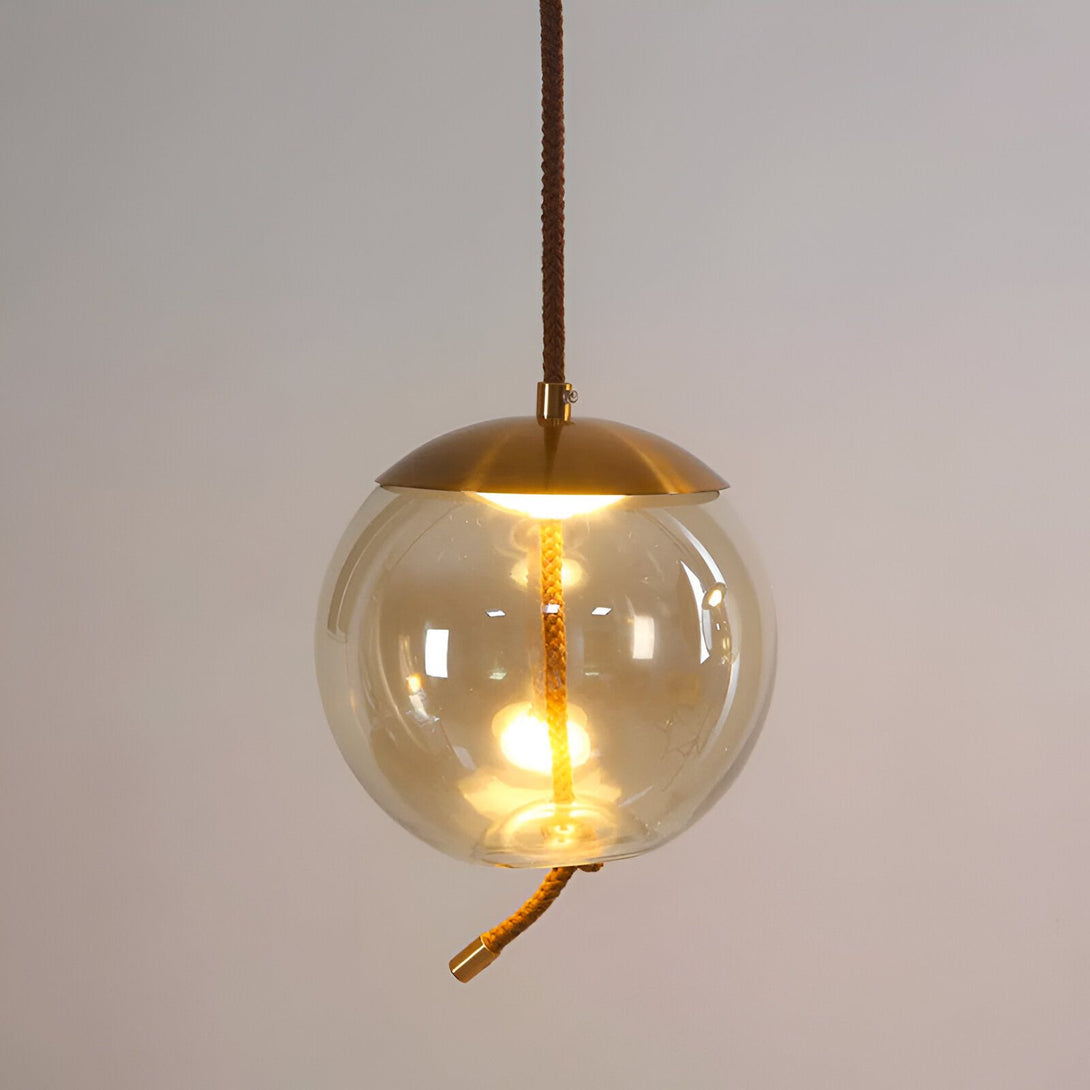 Une image d'un globe luminaire en verre. Le globe est en verre soufflé et possède une finition ambrée. Il est suspendu par un câble en cuivre tressé. Le luminaire est équipé d'une douille E27 et est compatible avec les ampoules LED. SE-8597680784,SE-9462870446,SE-7499298493,SE-0476608740,SE-2722836270,SE-3273417943,SE-5200325382,SE-3888024714,