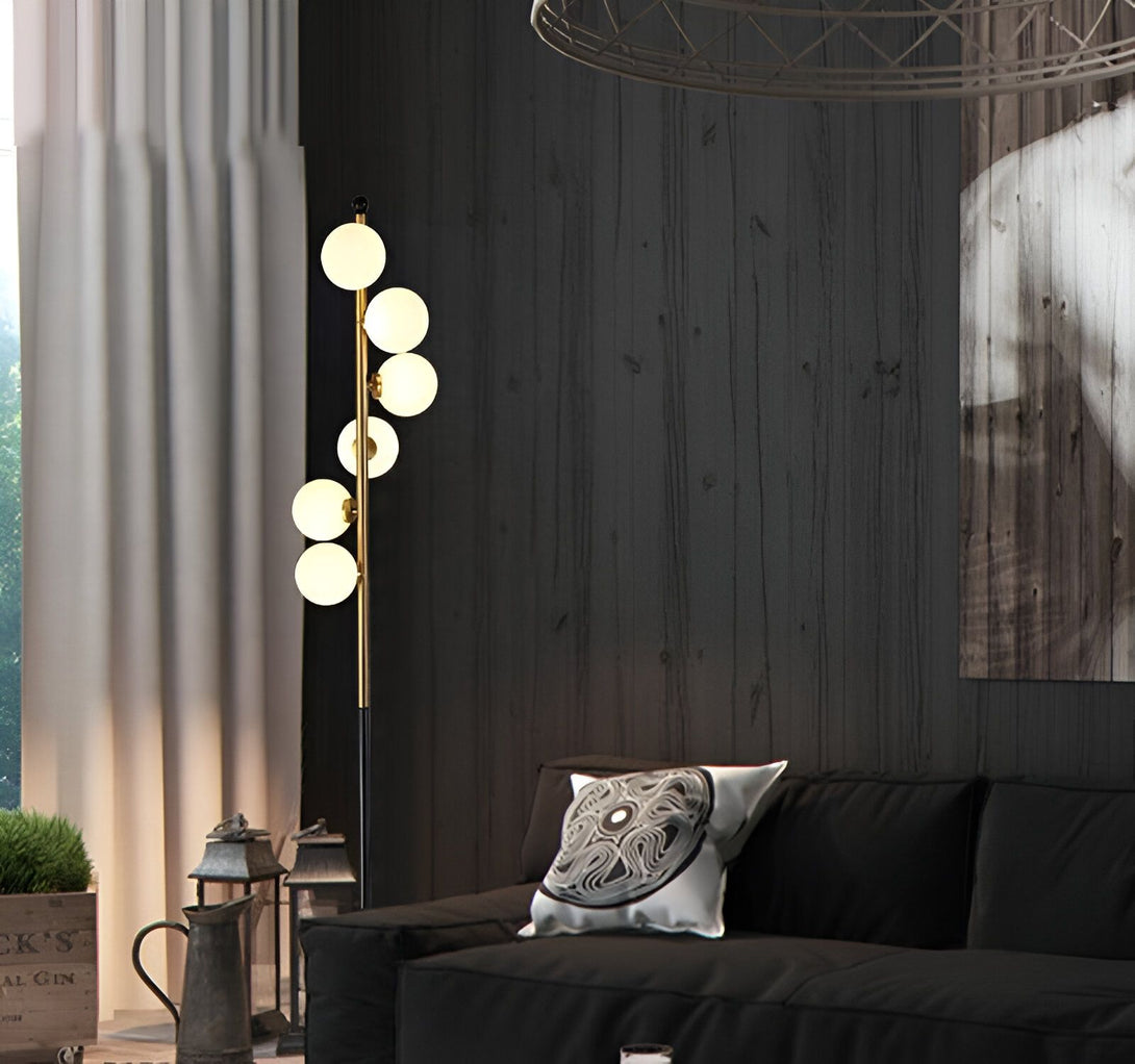 Un lampadaire doré avec cinq globes en verre opale est placé à côté d'un canapé noir dans un salon. HS-6263847484,