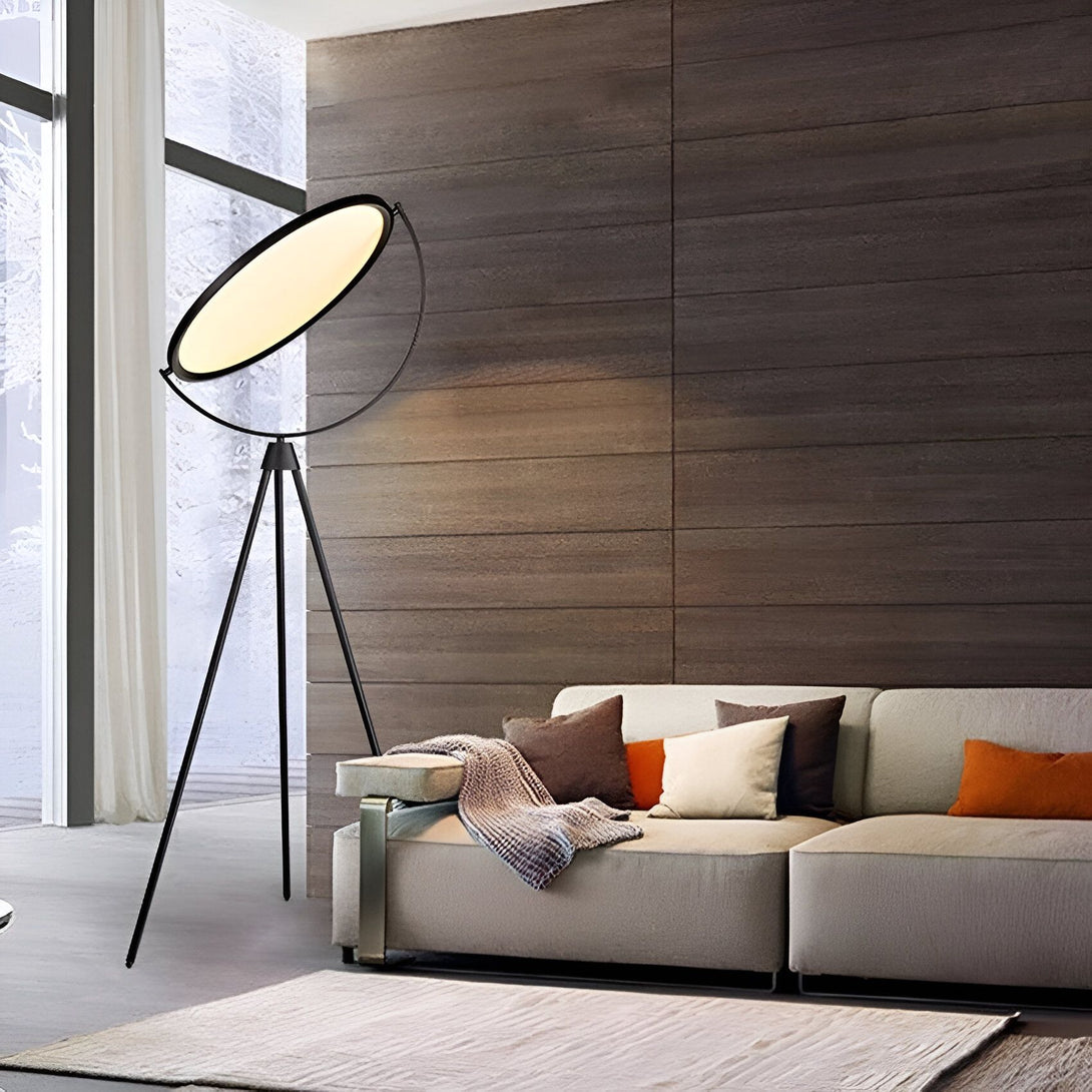 Un lampadaire noir avec un abat-jour rond et blanc est posé à côté d'un canapé gris dans un salon. Le lampadaire est posé sur un tapis marron. MA-1013807243,MA-235099841X,MA-249299418X,