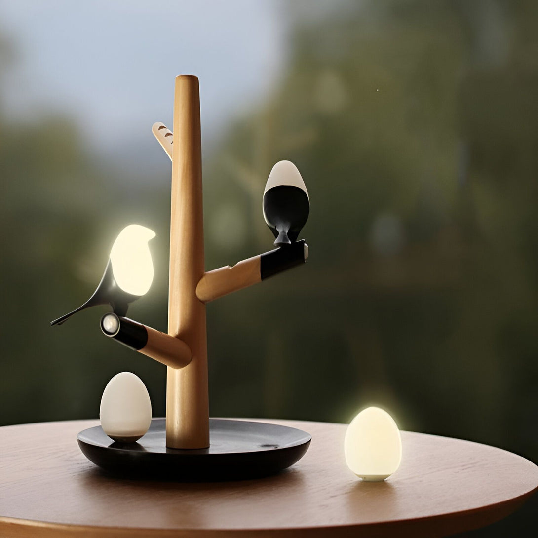 Une lampe en bois en forme d'arbre avec deux oiseaux et deux oeufs. Les oiseaux et les oeufs sont en céramique et émettent une lumière douce. BI-6459513236,BI-828669189X,