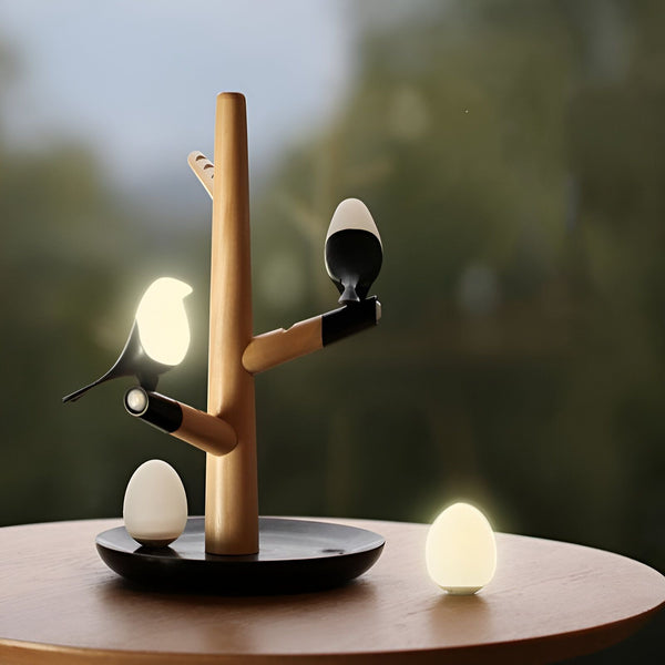 Une lampe en bois en forme d'arbre avec deux oiseaux et deux oeufs. Les oiseaux et les oeufs sont en céramique et émettent une lumière douce. BI-6459513236,BI-828669189X,