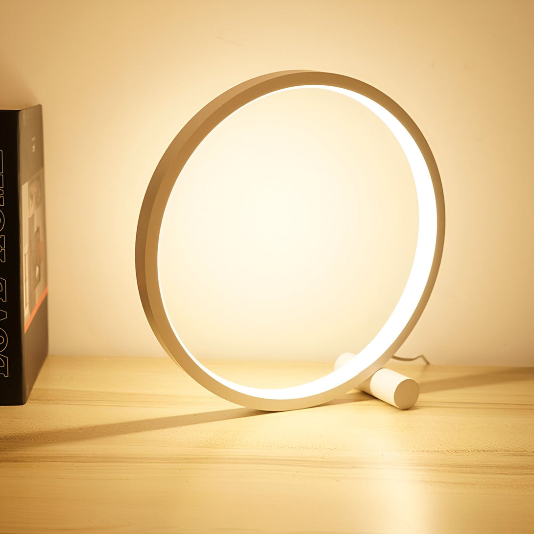 Une lampe de bureau LED blanche en forme d'anneau. La lampe est posée sur une table en bois. CE-4626626394,CE-0944412238,CE-2511648865,CE-0068266804,