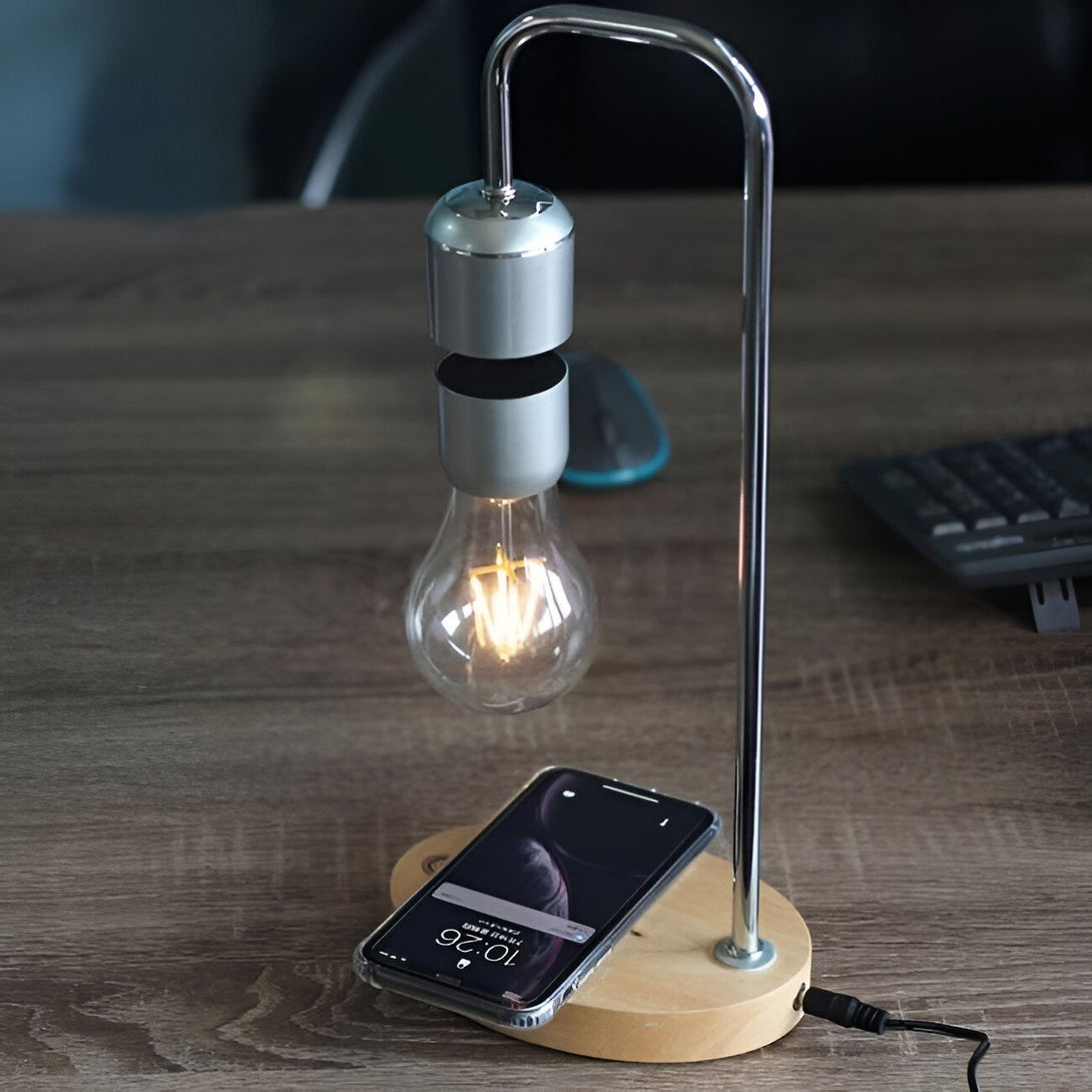 Une lampe à incandescence est suspendue au-dessus d'un socle en bois. Un téléphone portable est en charge sur le socle. LE-5812217572,