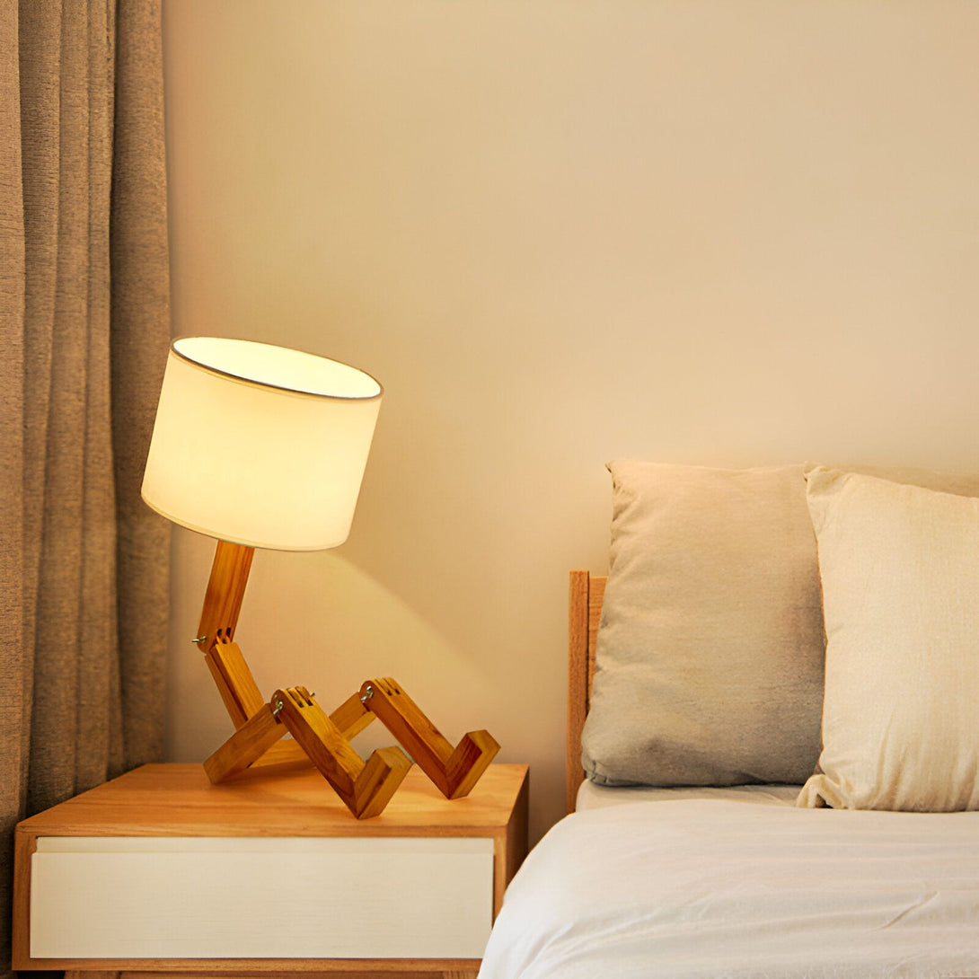 Une lampe de chevet en bois avec un abat-jour en tissu blanc est posée sur une table de chevet à côté d'un lit. LY-7887404320,LY-793791999X,