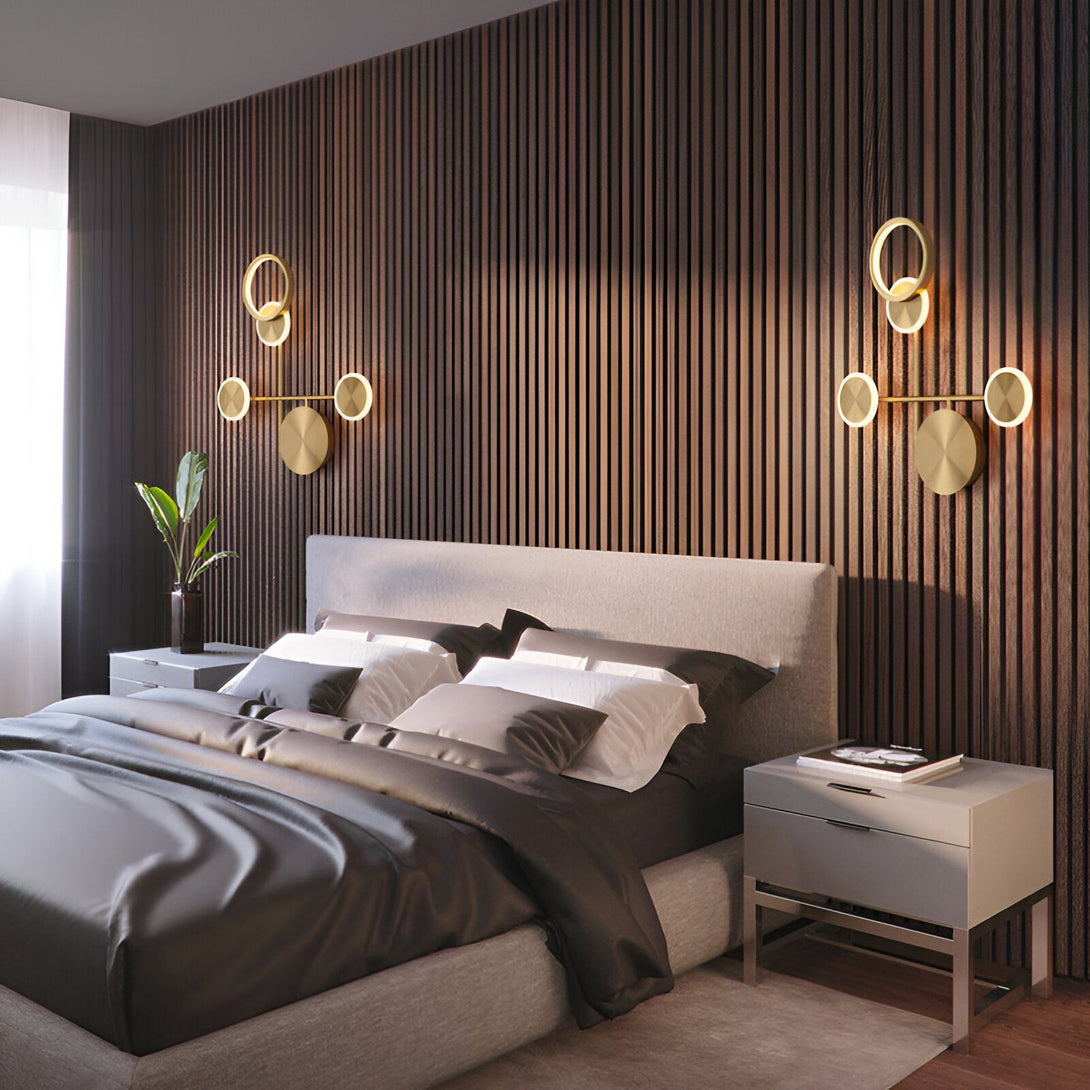 Une chambre à coucher avec un lit, une table de chevet, et deux appliques murales. Le lit est fait d'un cadre en bois avec une tête de lit capitonnée. La table de chevet est en bois avec un tiroir. Les appliques murales sont en métal doré avec un design moderne. DO-3701537453,DO-1406931985,DO-774364684X,DO-8119607104,