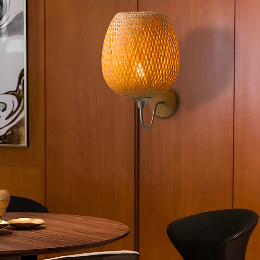 Une applique murale en bambou tressé diffuse une lumière tamisée dans une salle à manger. PE-1502754312,PE-072362576X,