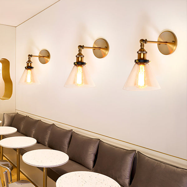 Une image de trois appliques murales industrielles en laiton avec des abat-jours en verre transparent. Les appliques sont fixées au mur et diffusent une lumière chaleureuse. YT-4255477396,YT-8153868179,