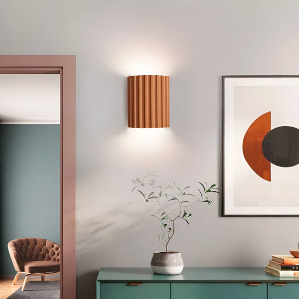 Une image d'une applique murale en céramique côtelée marron. À côté, il y a une plante verte sur une commode verte. Il y a aussi un cadre avec un cercle marron et noir. NE-721526775X,NE-8904744822,NE-2805852109,NE-679239677X,