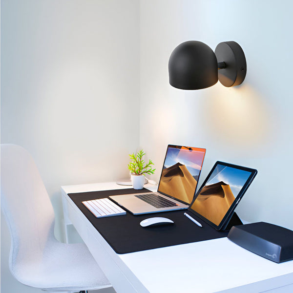 Une image d'une applique murale tactile noire. L'applique murale est fixée au mur au-dessus d'un bureau. Il y a un ordinateur portable, une tablette et une souris sur le bureau. L'applique murale est allumée et émet une lumière blanche chaude. ZE-961429731X,ZE-7006801699,ZE-8282532002,ZE-5116487288,