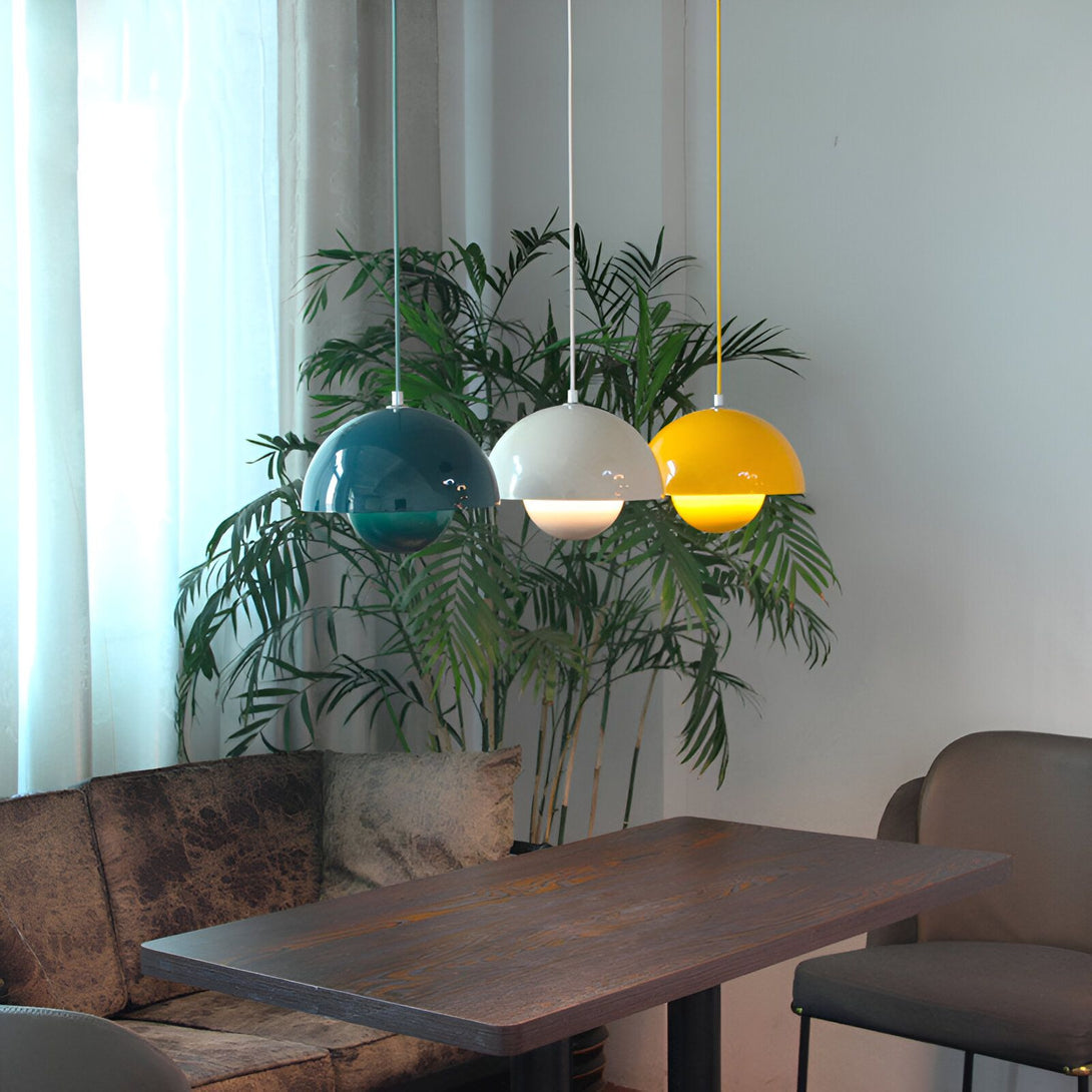 Trois suspensions en forme de demi-sphère de couleur bleu canard, blanche et jaune. Elles sont accrochées au plafond par un fil électrique et éclairent une table à manger en bois. ET-2088625054,ET-4141448087,ET-3713567360,ET-9366259863,ET-968898597X,ET-4184751059,ET-4381876865,ET-4450445309,