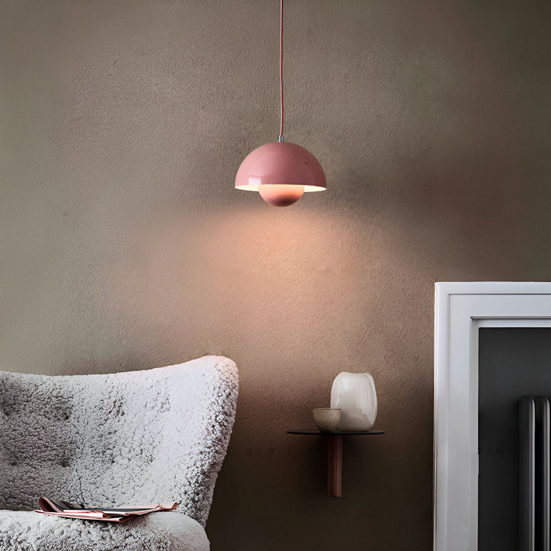 Une image d'une lampe suspension rose en forme de tulipe. La lampe est suspendue au plafond par un fil rose. Il y a un mur marron en arrière-plan et un canapé beige avec une peau de mouton dessus. Il y a une petite table en bois avec un vase et une bougie dessus. ET-2088625054,ET-4141448087,ET-3713567360,ET-9366259863,ET-968898597X,ET-4184751059,ET-4381876865,ET-4450445309,