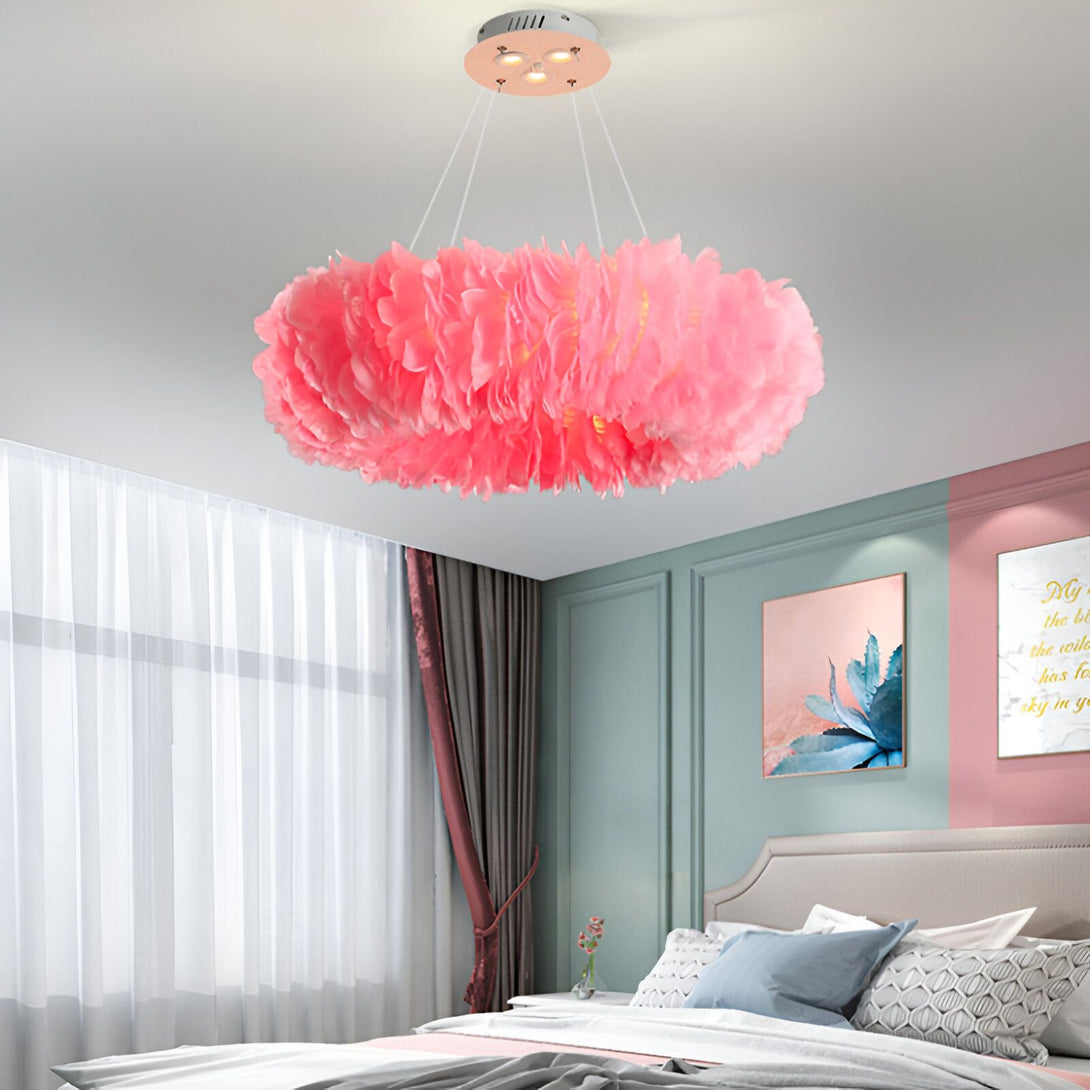 Une image d'un lustre rose en forme de fleur. Il est suspendu au plafond et est fait de plumes d'autruche. Le lustre est allumé et diffuse une lumière douce et tamisée.