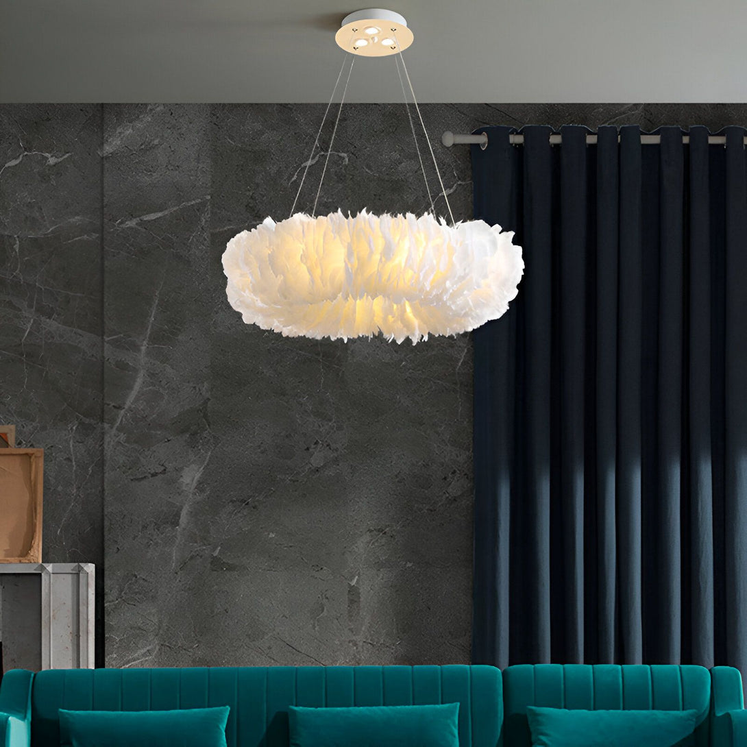 L'image montre un lustre rond en plumes blanches. Il est suspendu au plafond et éclairé par une lumière blanche. Le lustre est entouré de rideaux bleus et de murs en marbre gris.